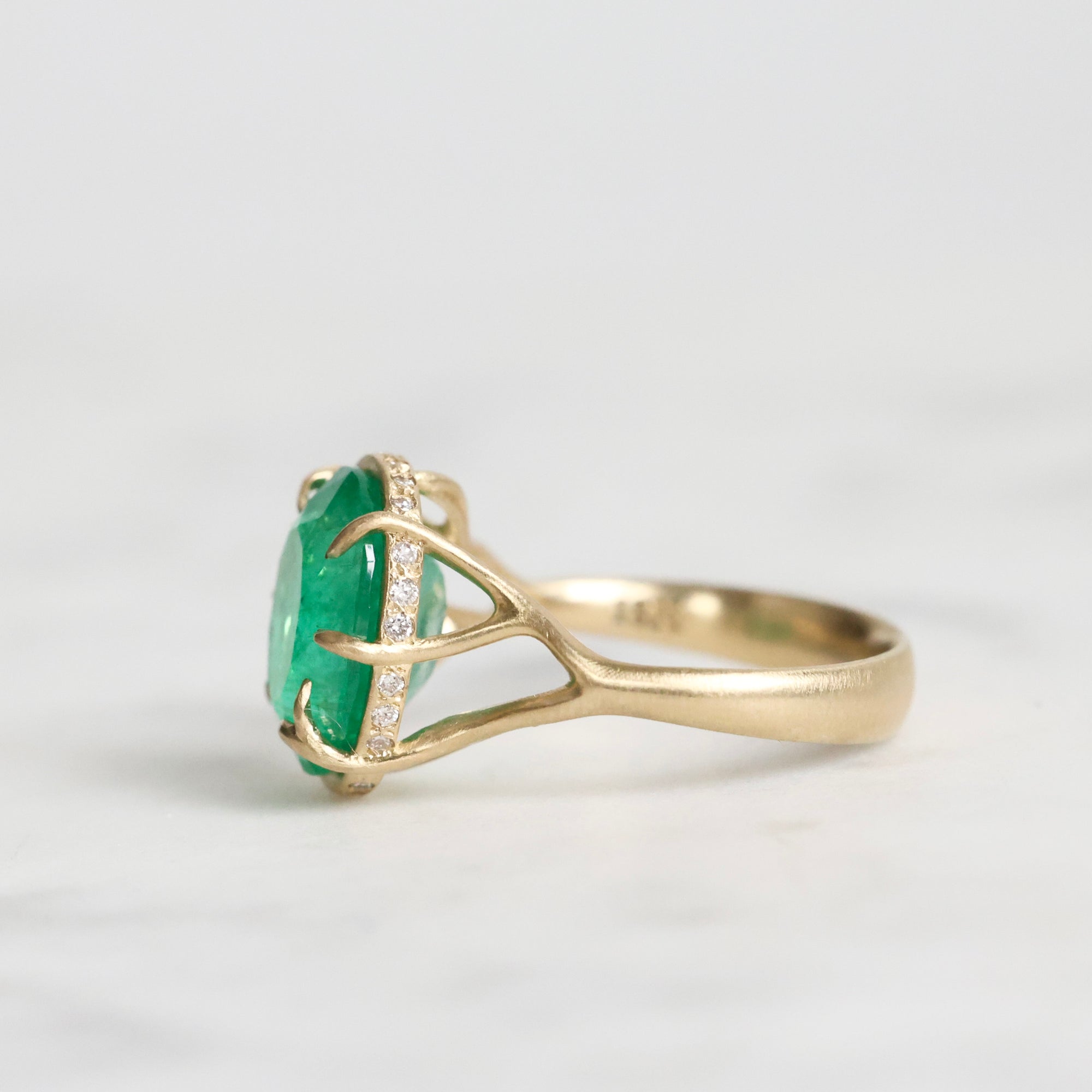 Large green gemstone ring with a diamond halo and branchy setting