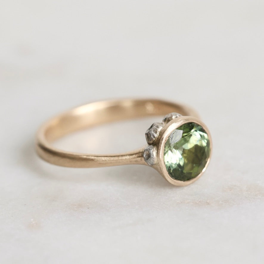 Gold ring with a green gemstone on a light background