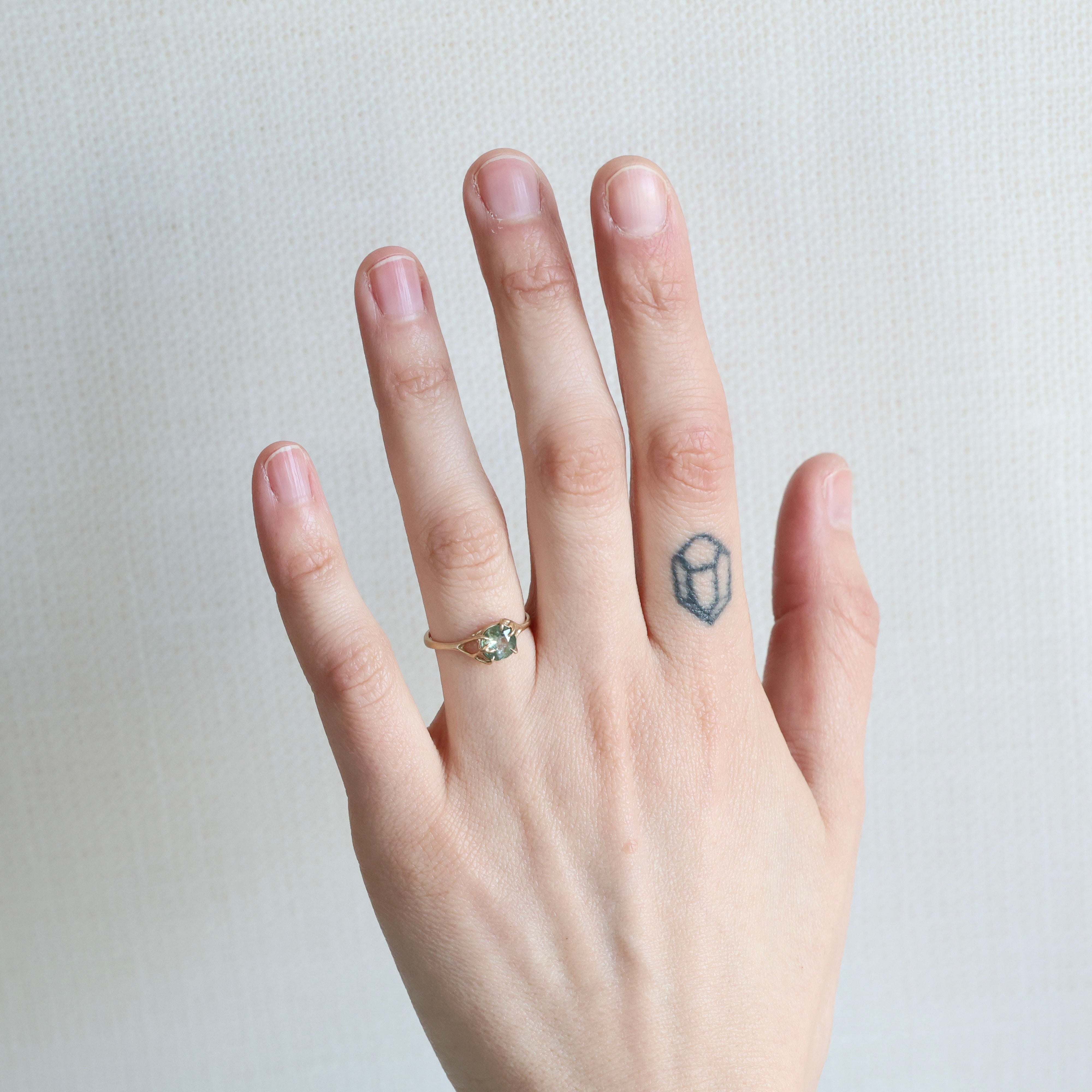 Hand with a ring and a small tattoo on a plain background