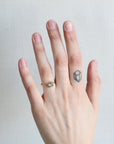 Hand with a ring and a small tattoo on a plain background