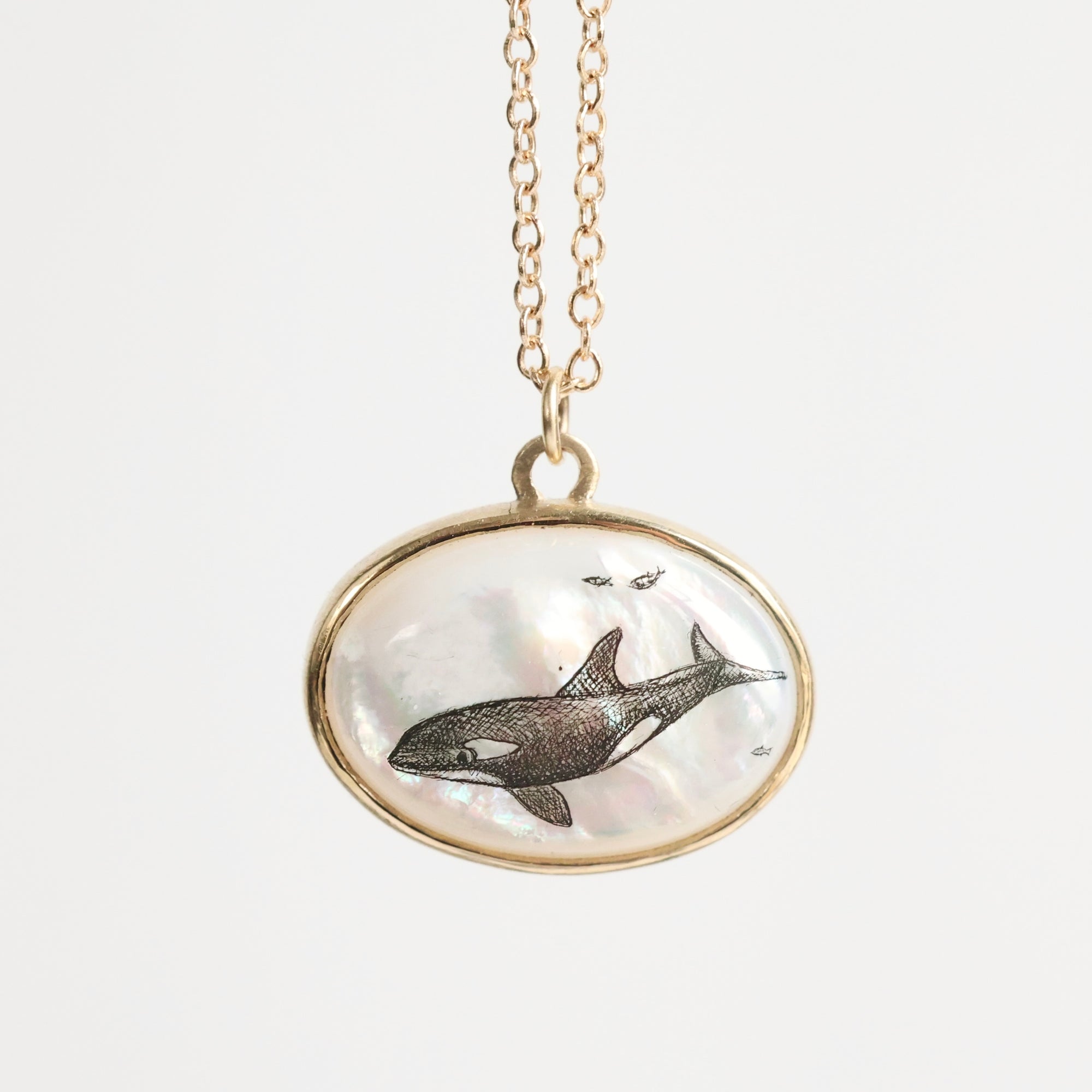 Necklace with a pendant featuring an orca whale design on a light gray background