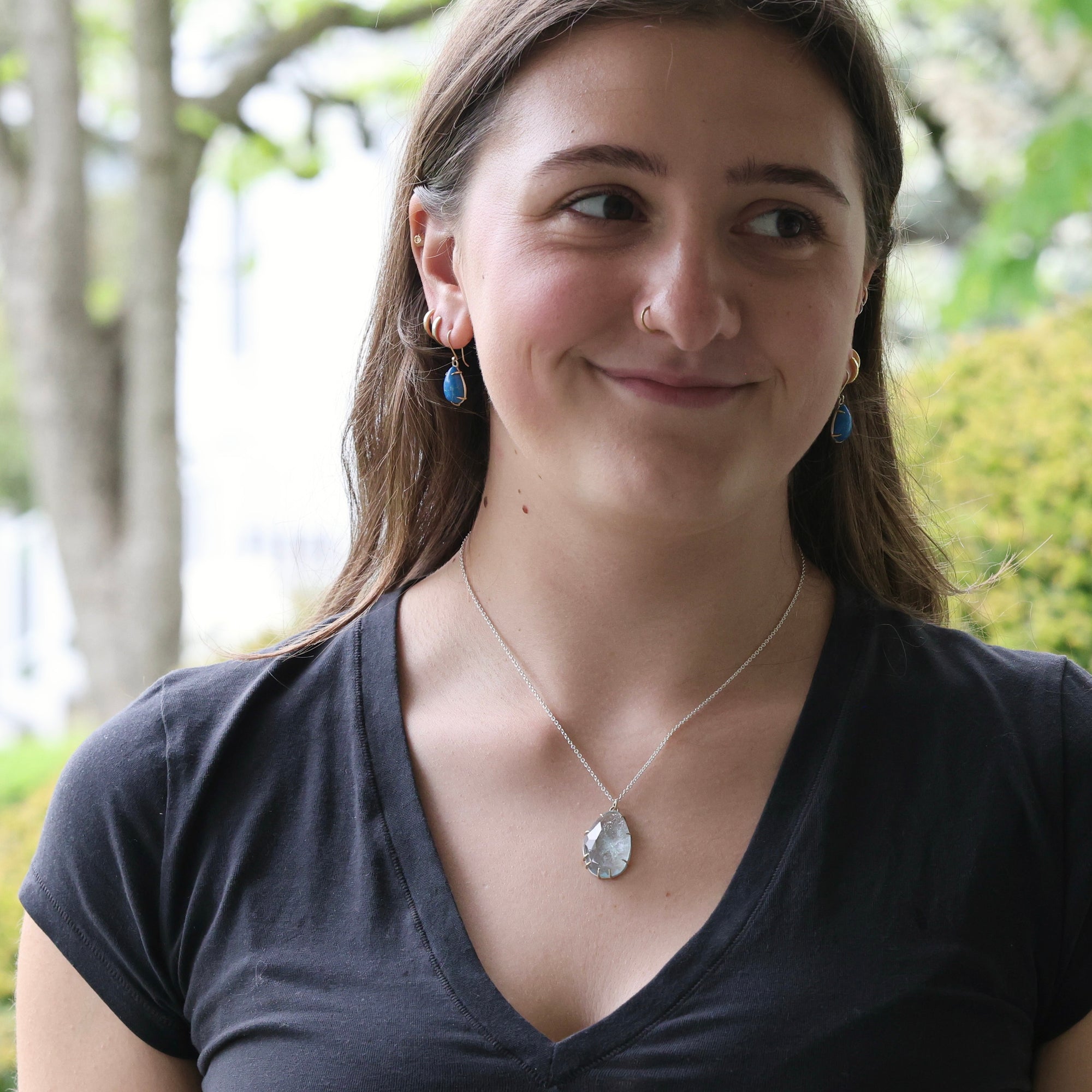 Woman wearing necklace with large blue gemstone outside