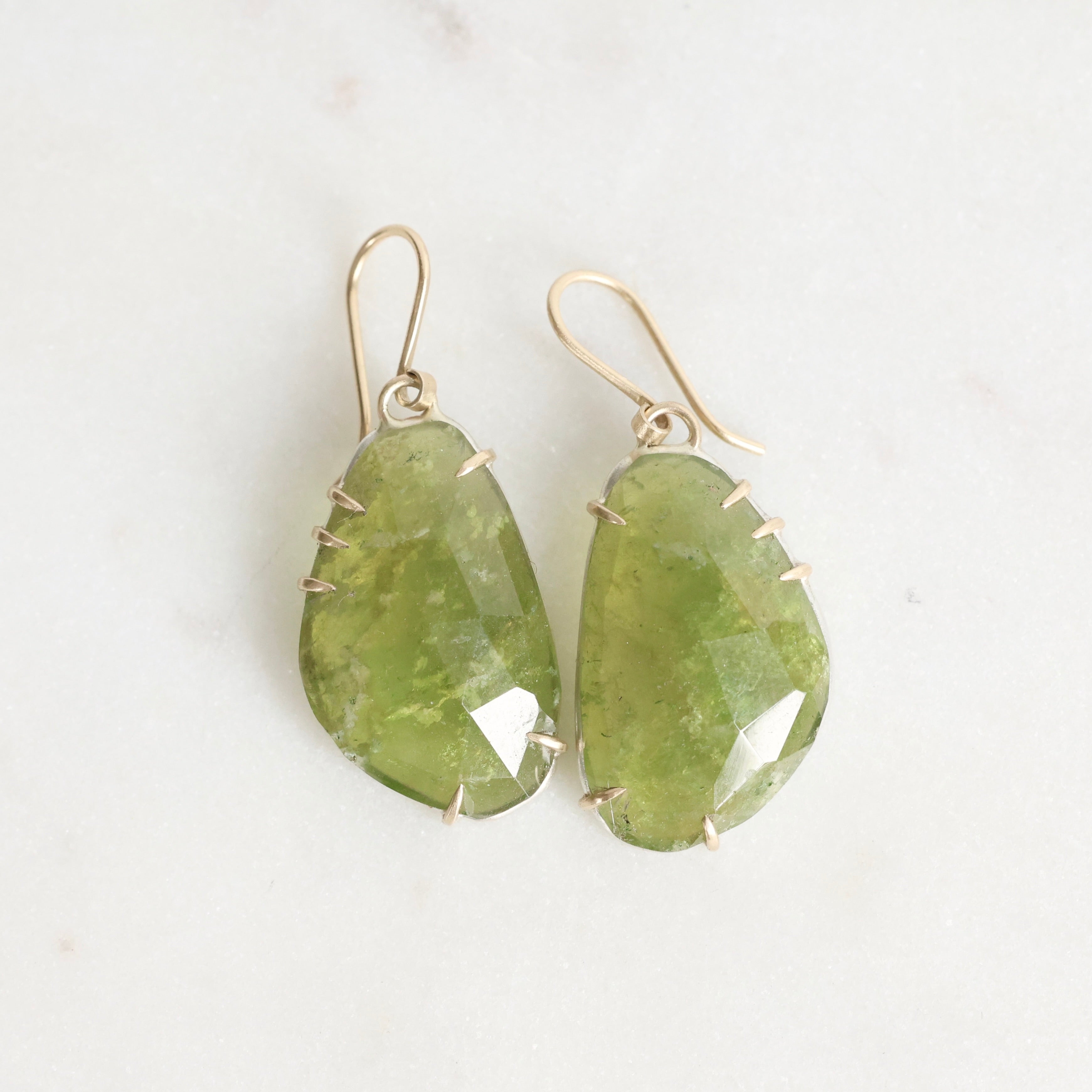 Green teardrop earrings on a light background