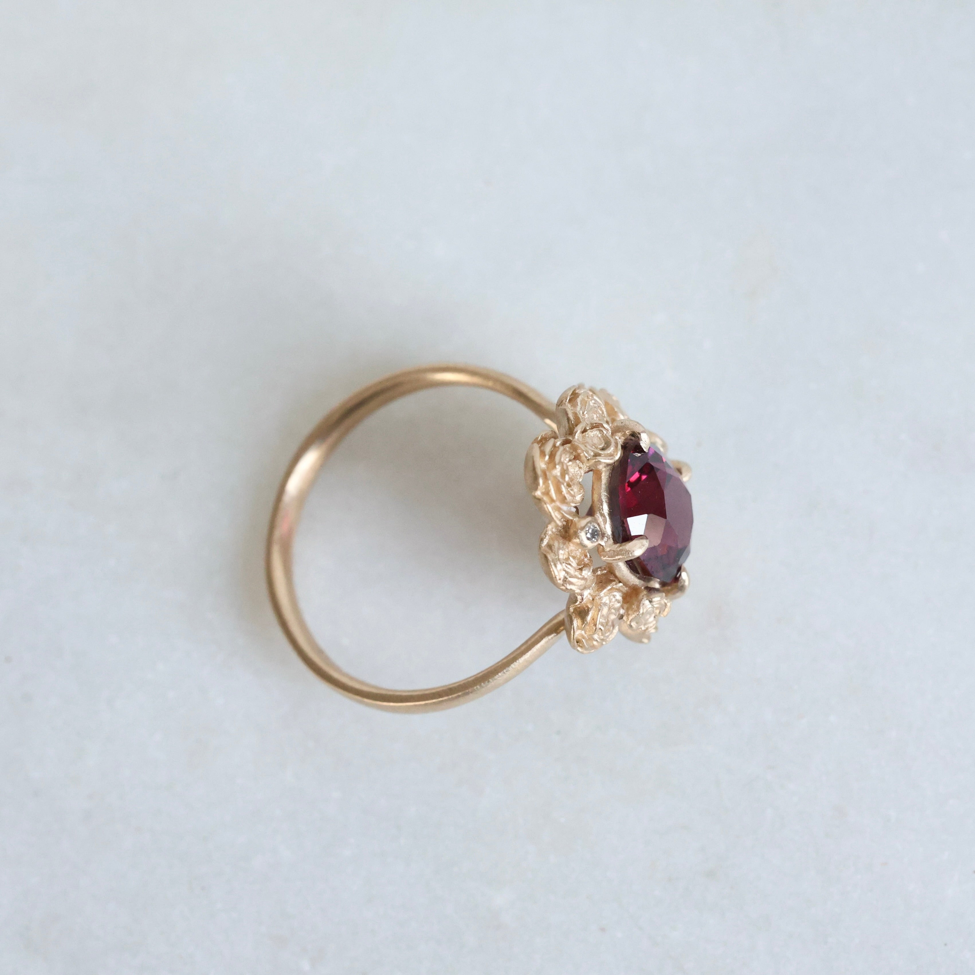 Gold ring with a red gemstone on a light gray background