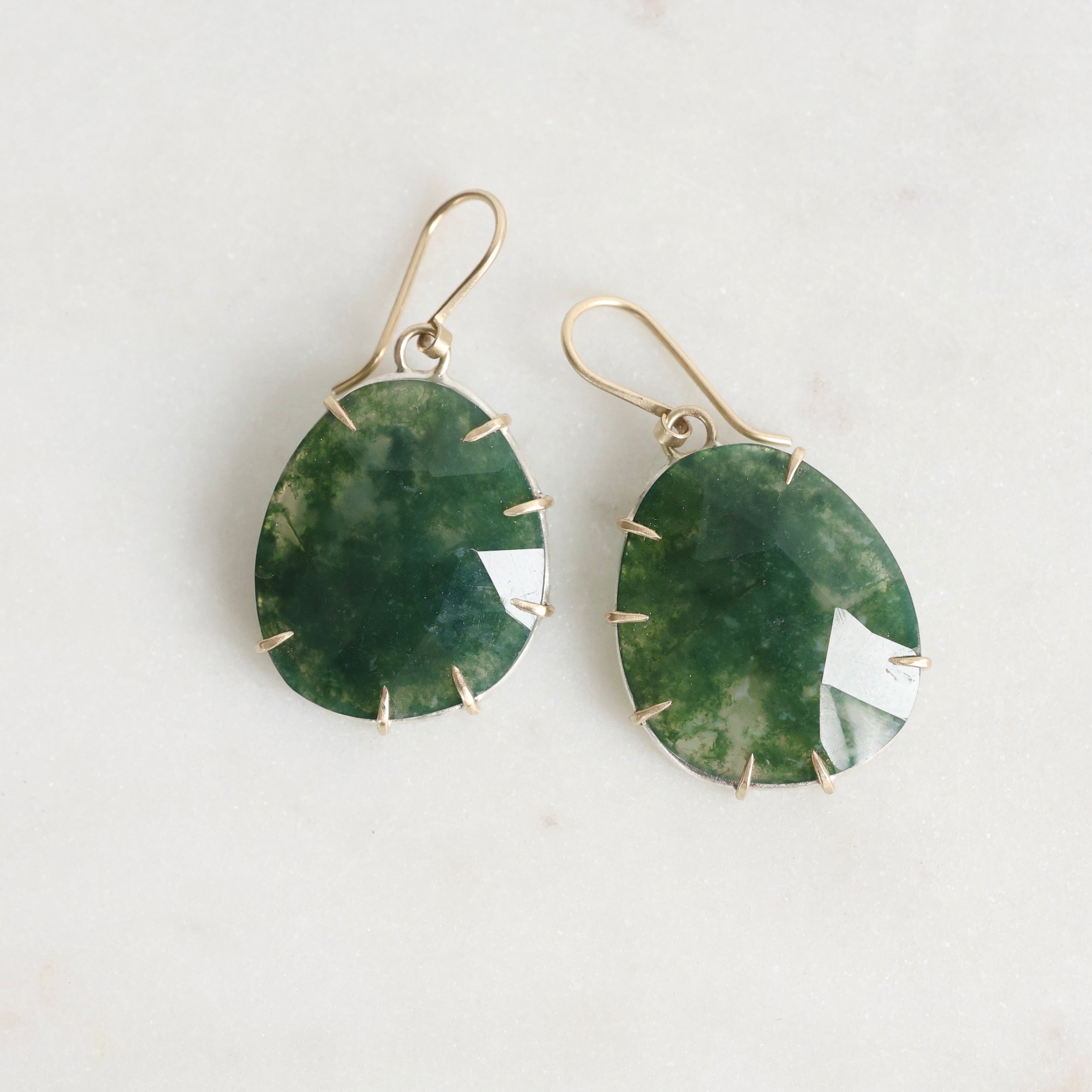 Green stone earrings with gold accents on a white background
