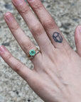 gold barnacle band on hand with green gemstone ring 