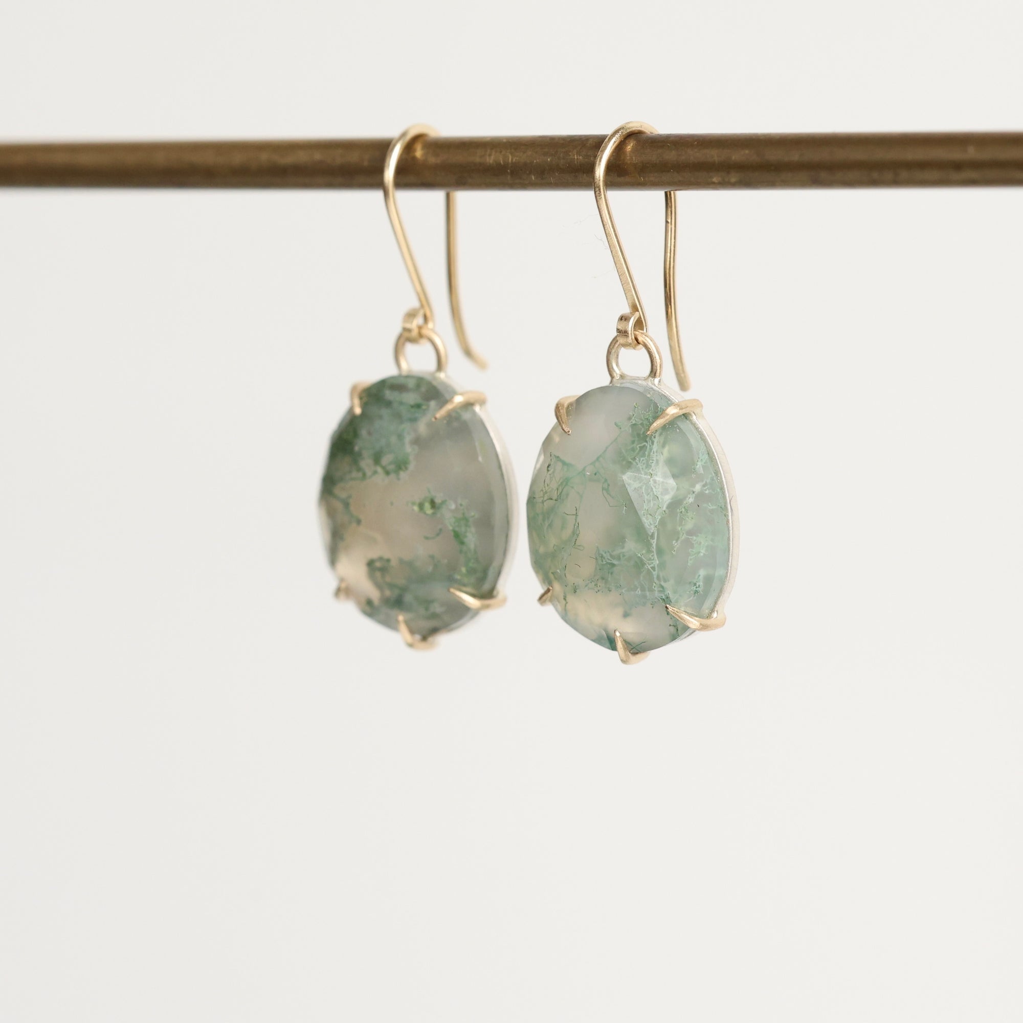 pair of green stone earrings from the side against a white background