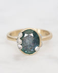 Gold ring with a large green gemstone and smaller diamonds on a white background
