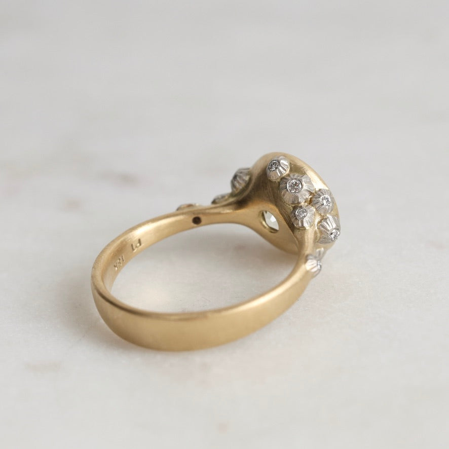 Gold ring with diamond accents on a light gray background