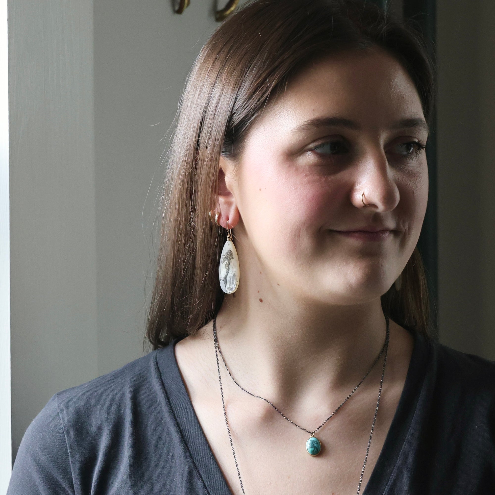 Woman wearing earrings and a necklace with a blurred background