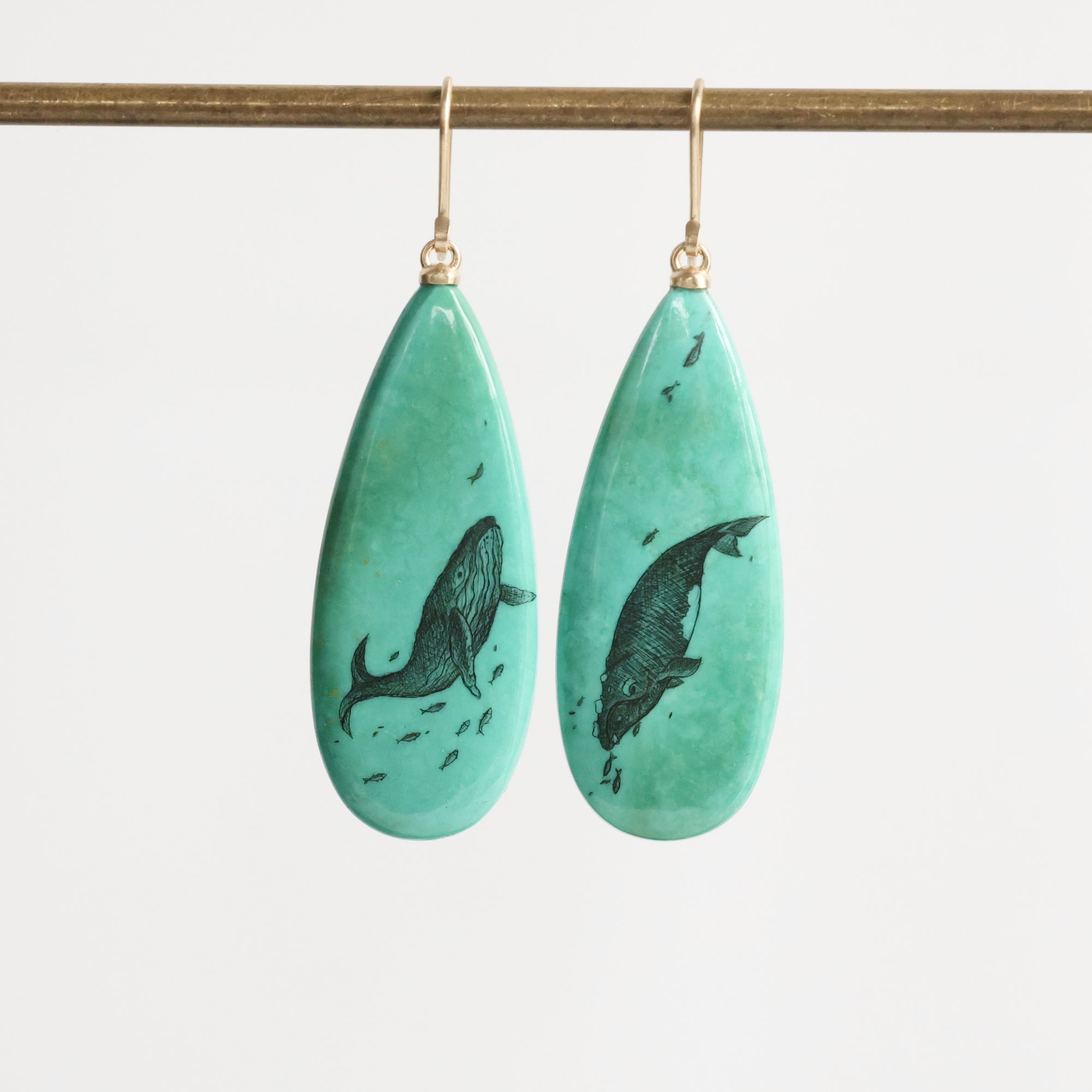 Teardrop-shaped earrings with whale design on a white background