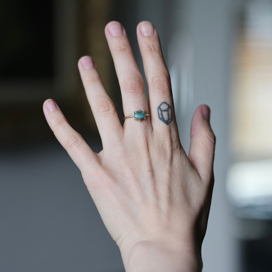 Hand wearing green stone ring in prongs