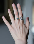 Hand wearing green stone ring in prongs