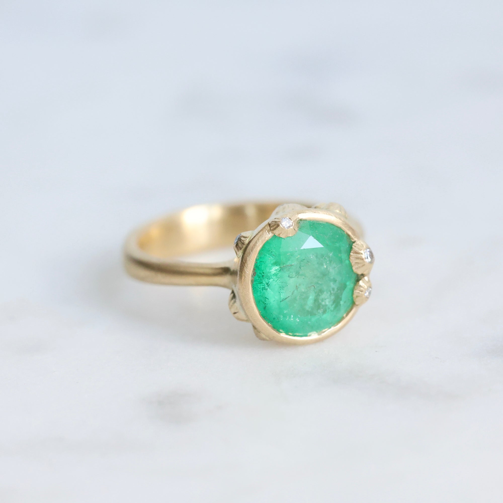Large green gemstone ring surrounded by gold barnacles with diamonds 