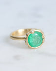 Large green gemstone ring surrounded by gold barnacles with diamonds 