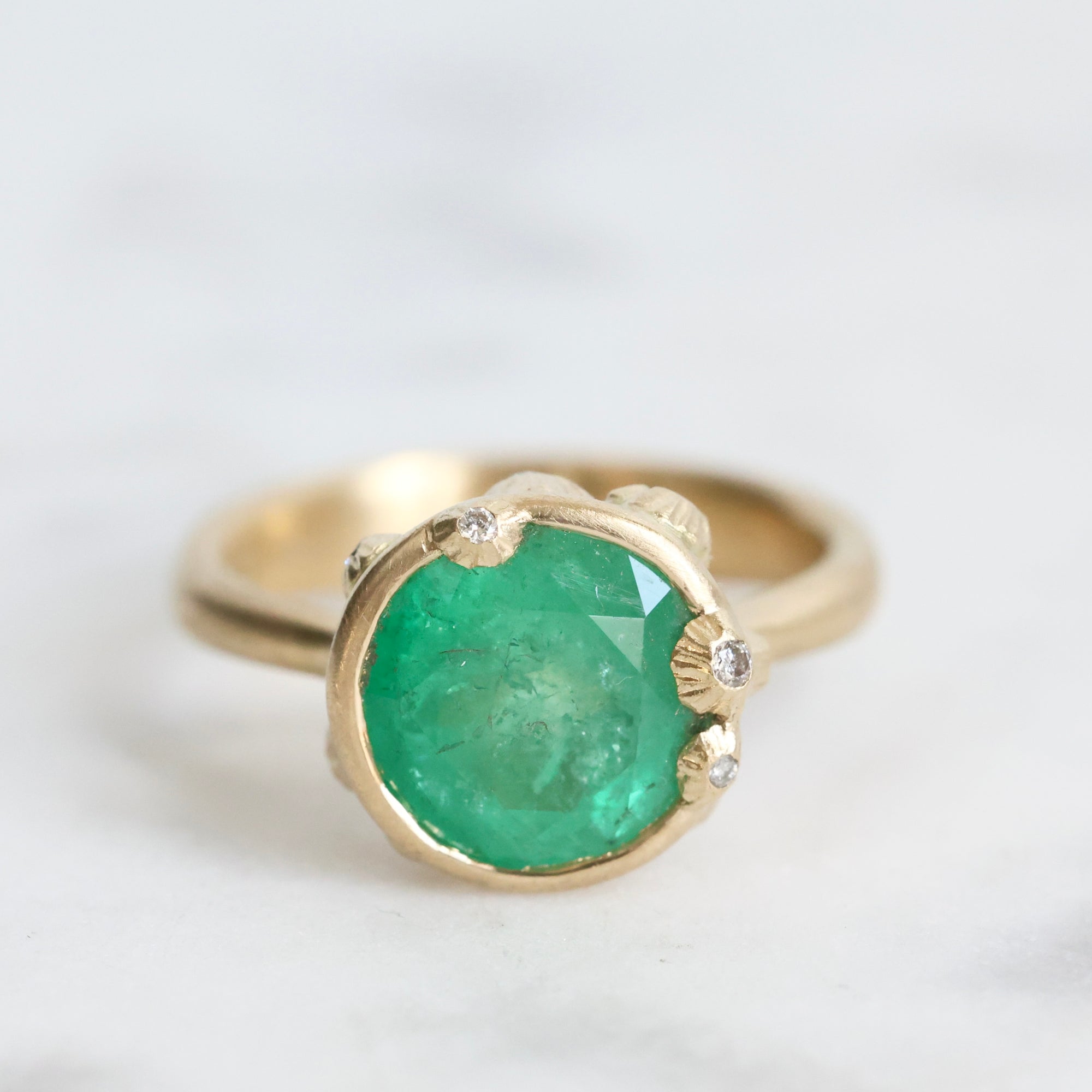 Large green gemstone ring surrounded by gold barnacles with diamonds 