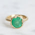 Large green gemstone ring surrounded by gold barnacles with diamonds 