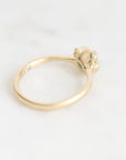 A delicate yellow gold ring photographed on a light, neutral background.