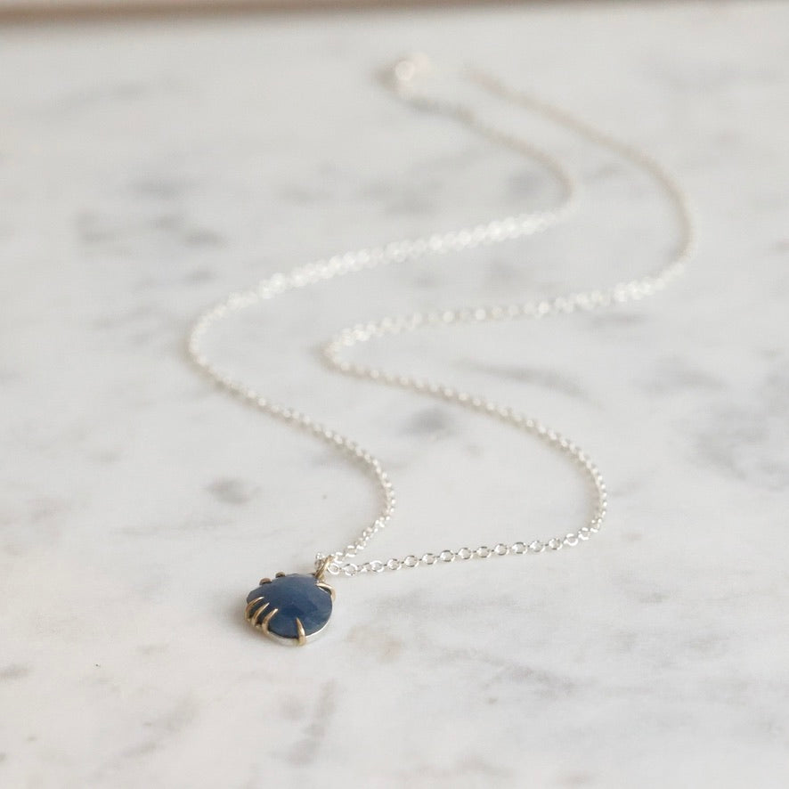 Necklace with a blue pendant on a marble surface