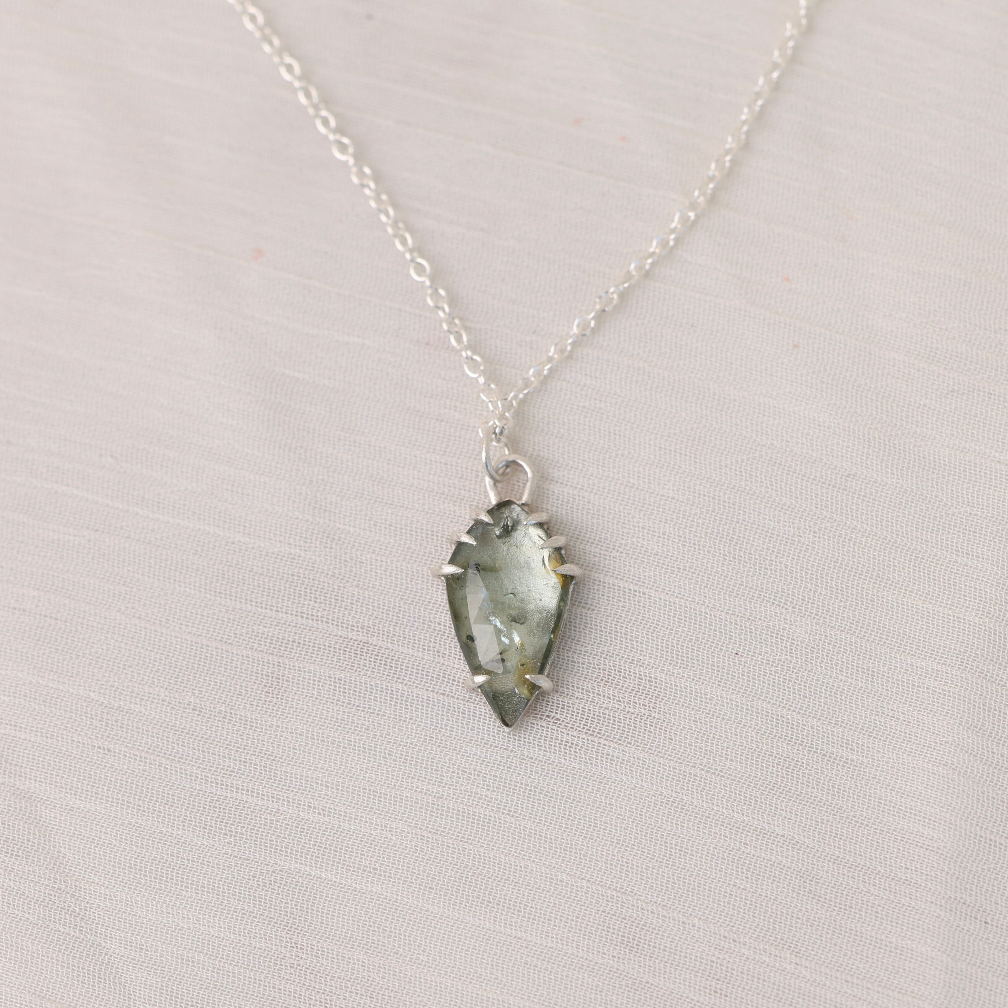 Necklace with a green crystal pendant on a light gray background