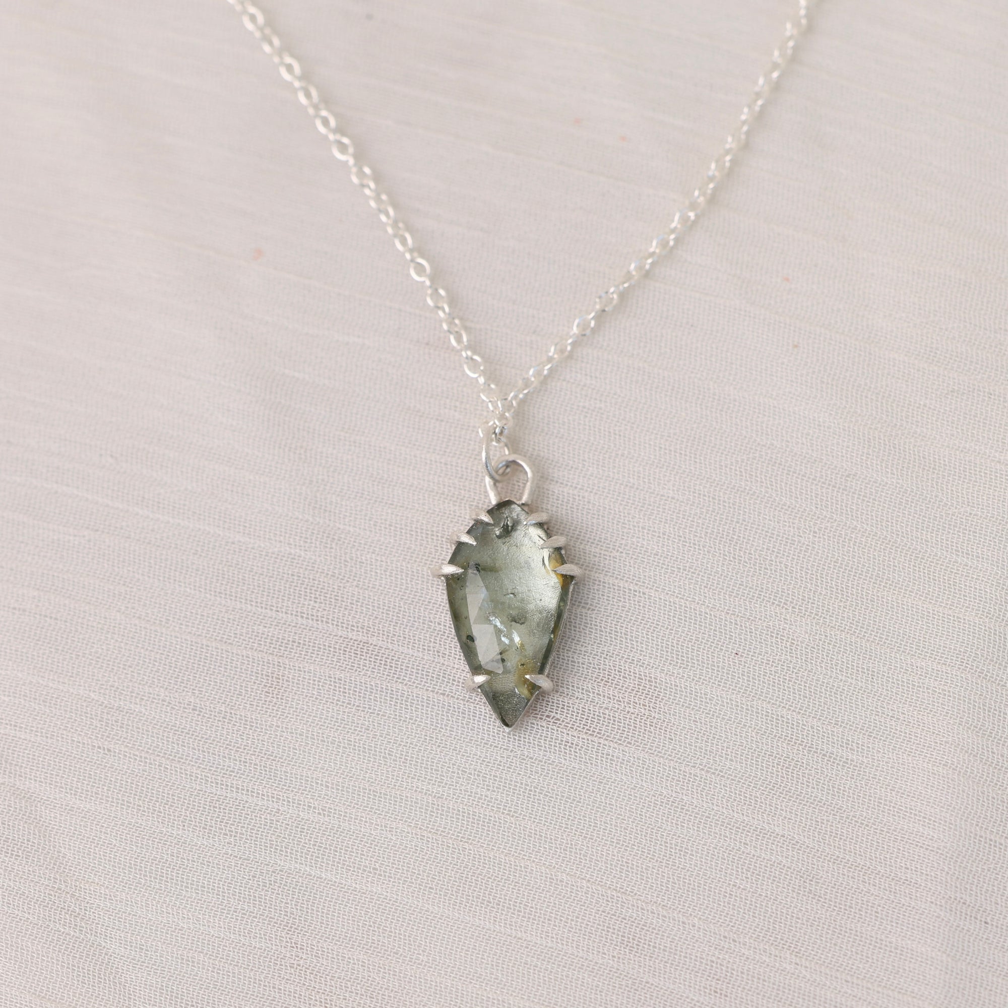 Necklace with a green crystal pendant on a light gray background