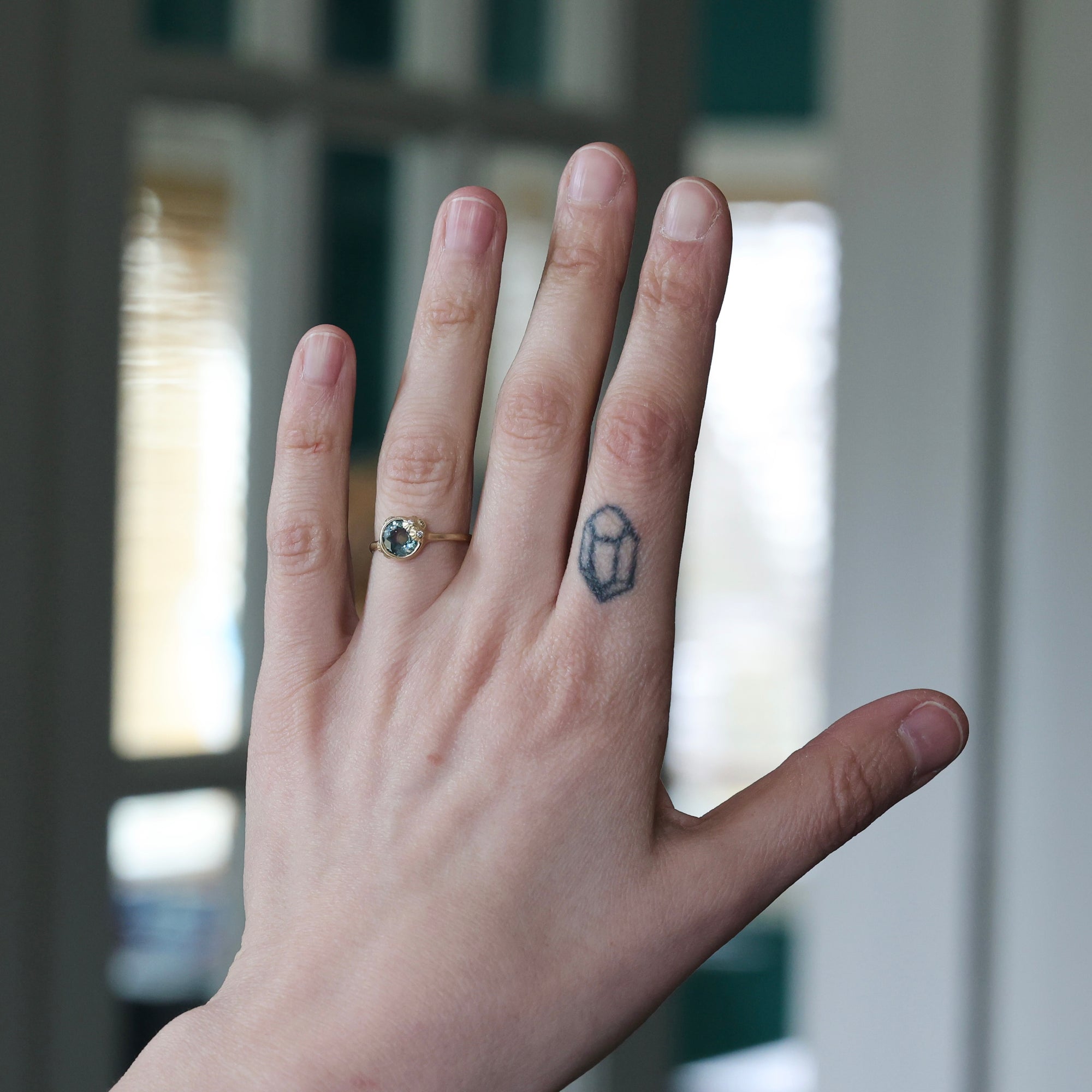 Hand with a ring and tattoo, blurred background