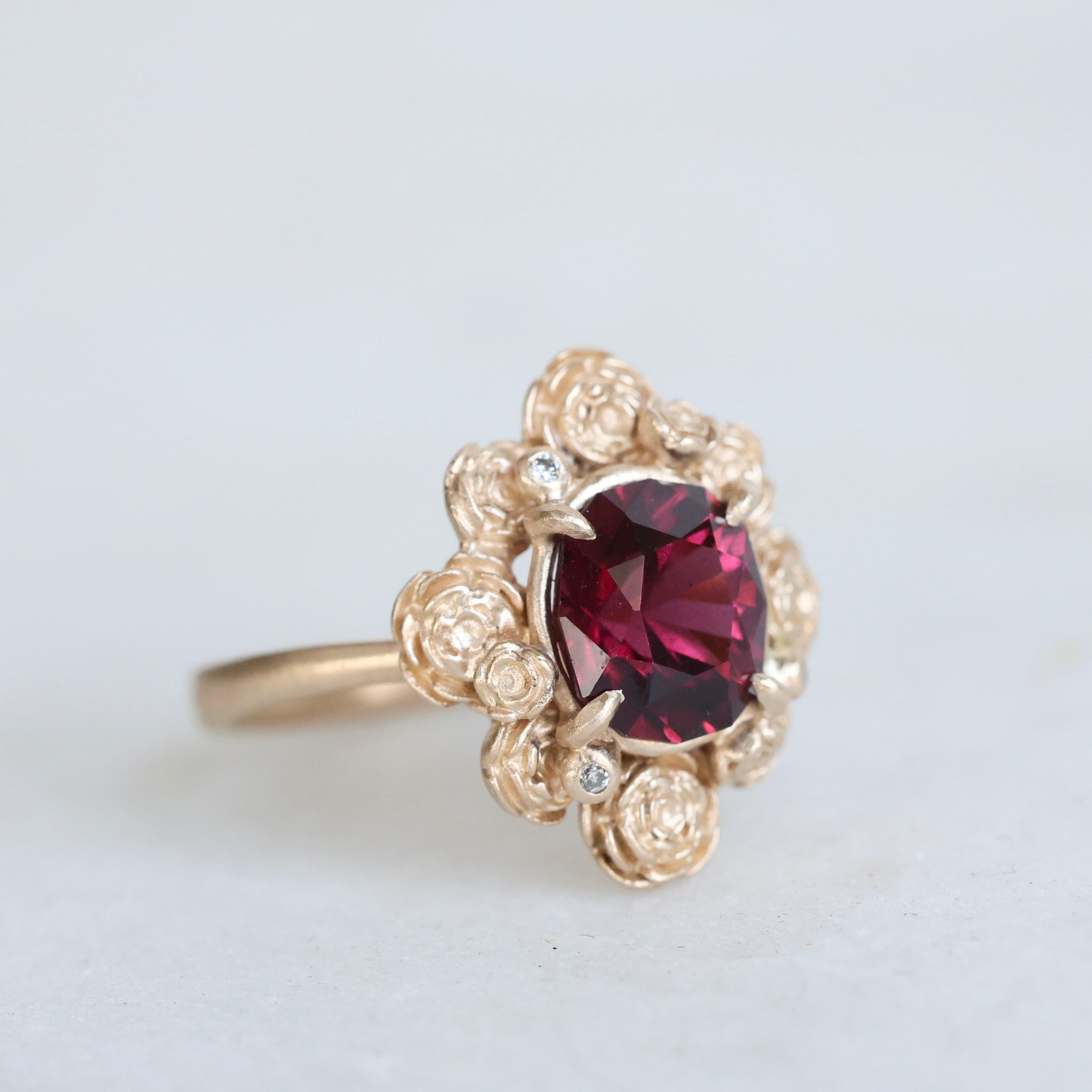 Gold ring with a red gemstone on a light gray background