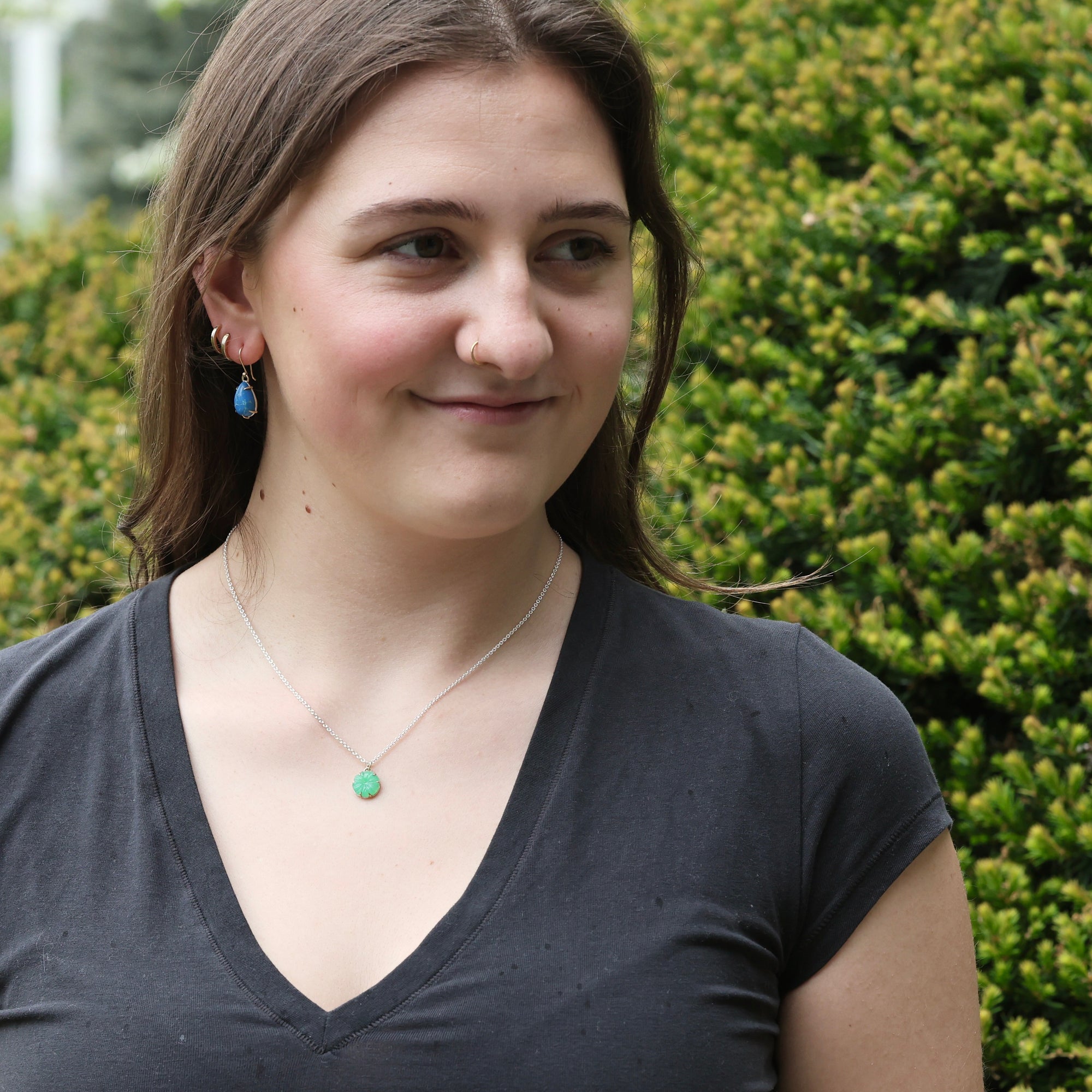 woman wearing necklace with green pendant outside