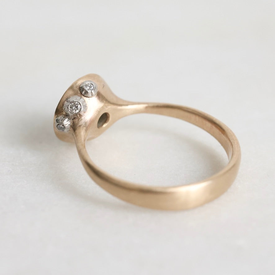 Gold ring with three small diamonds on a light gray background