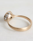 Gold ring with three small diamonds on a light gray background