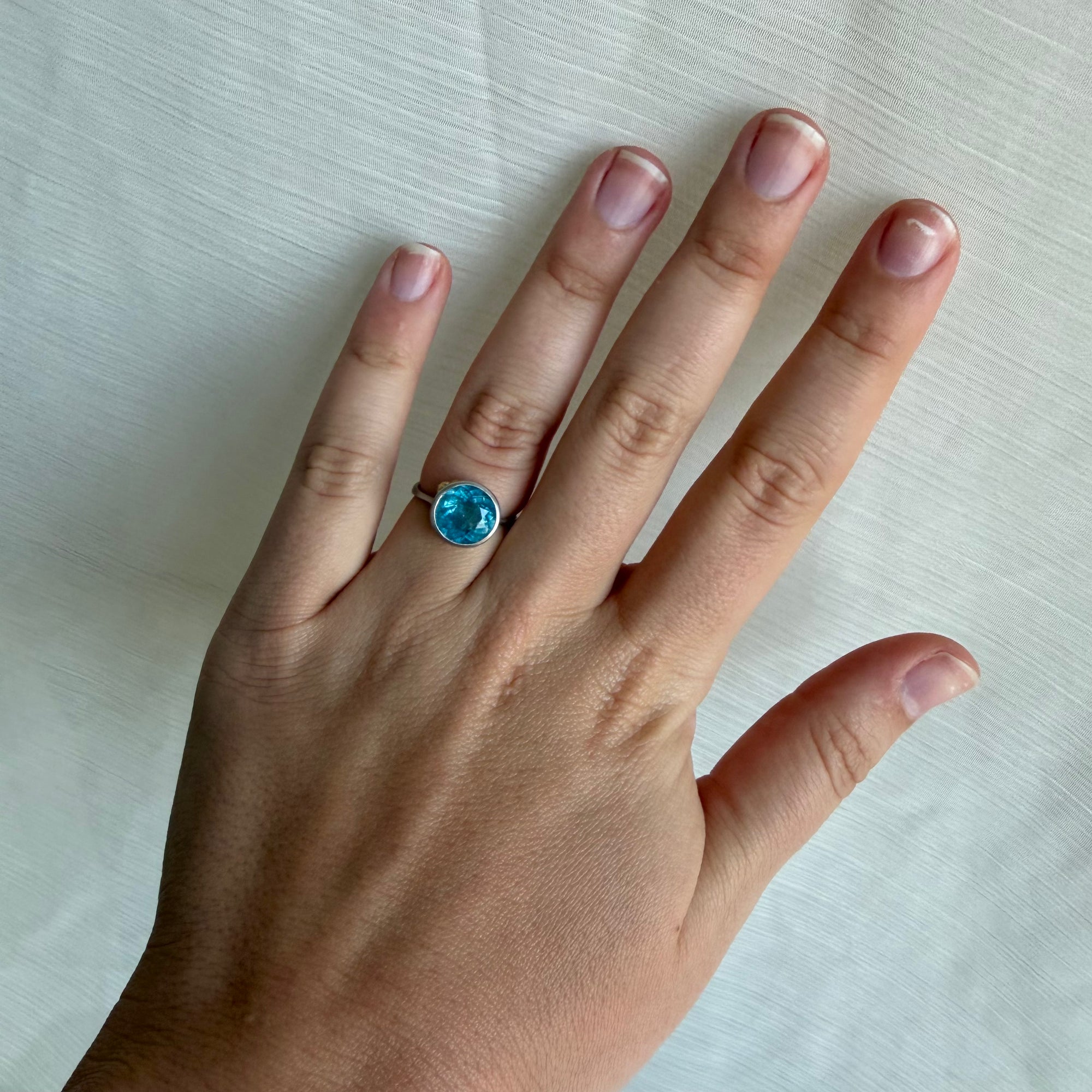 Blue stone ring on hand with a white background
