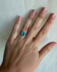 Blue stone ring on hand with a white background