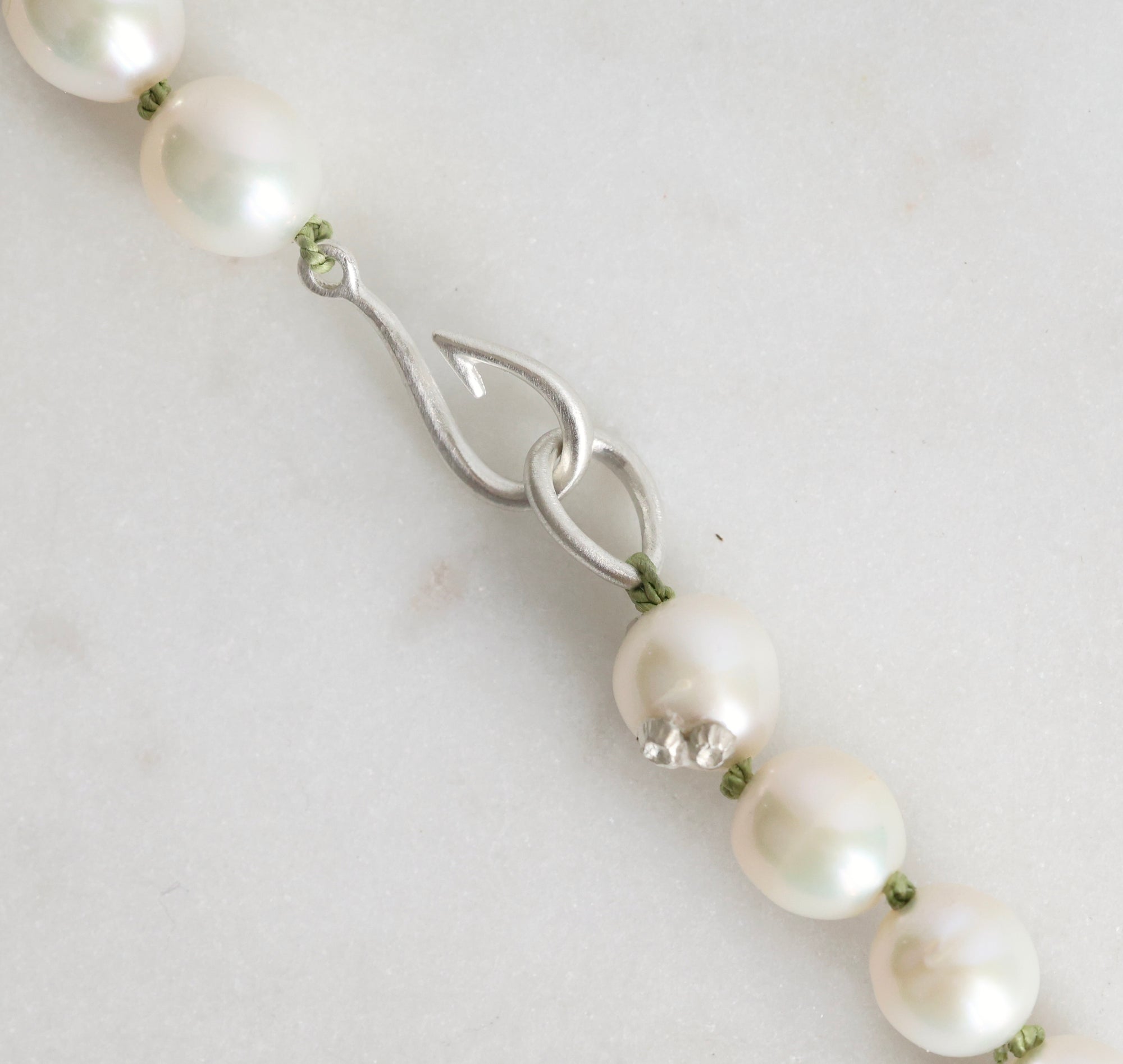 Pearl necklace with a silver clasp on a light gray background
