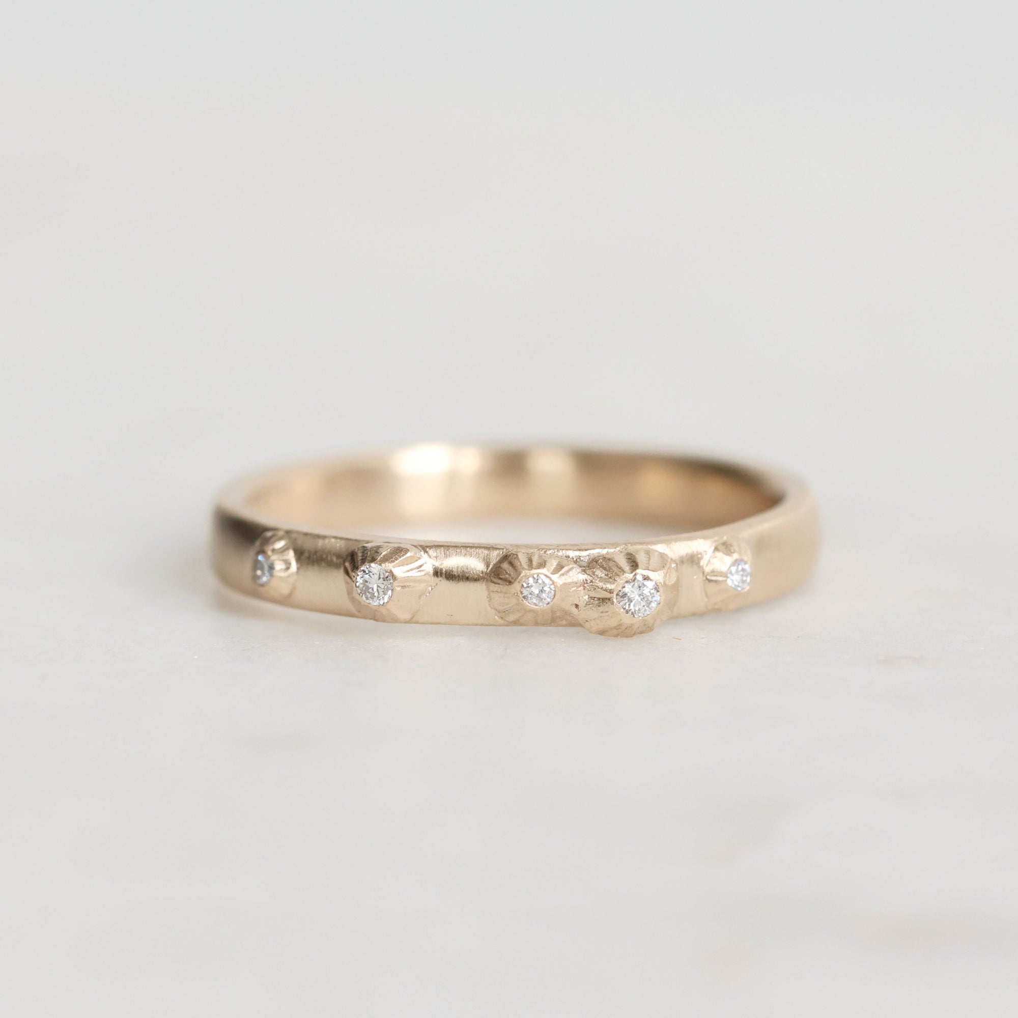 Gold ring with embedded diamonds on a light gray background