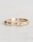 Gold ring with embedded diamonds on a light gray background