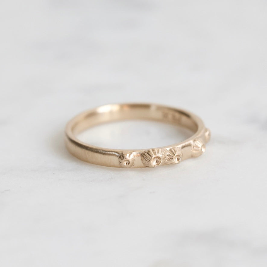 Gold ring with engraved design on a light gray background