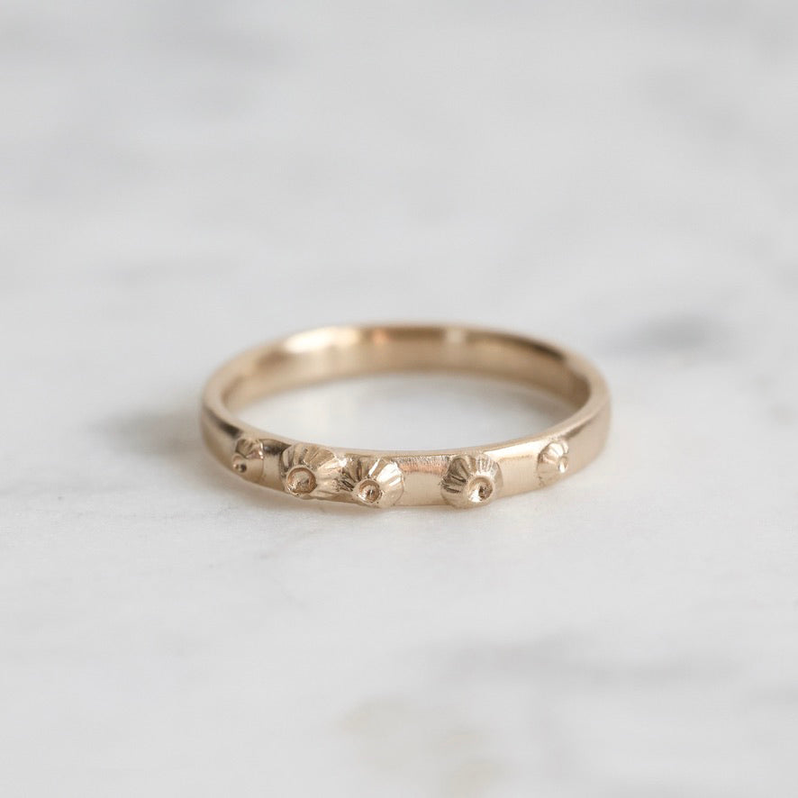 Gold ring with floral designs on a light gray background