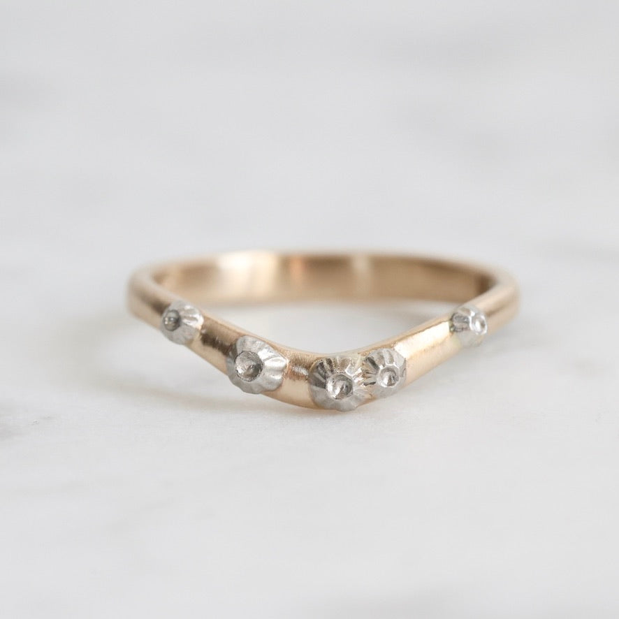 Gold ring with small barnacle details on a light gray background