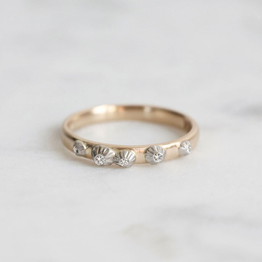 Gold ring with barnacle designs on a light gray background