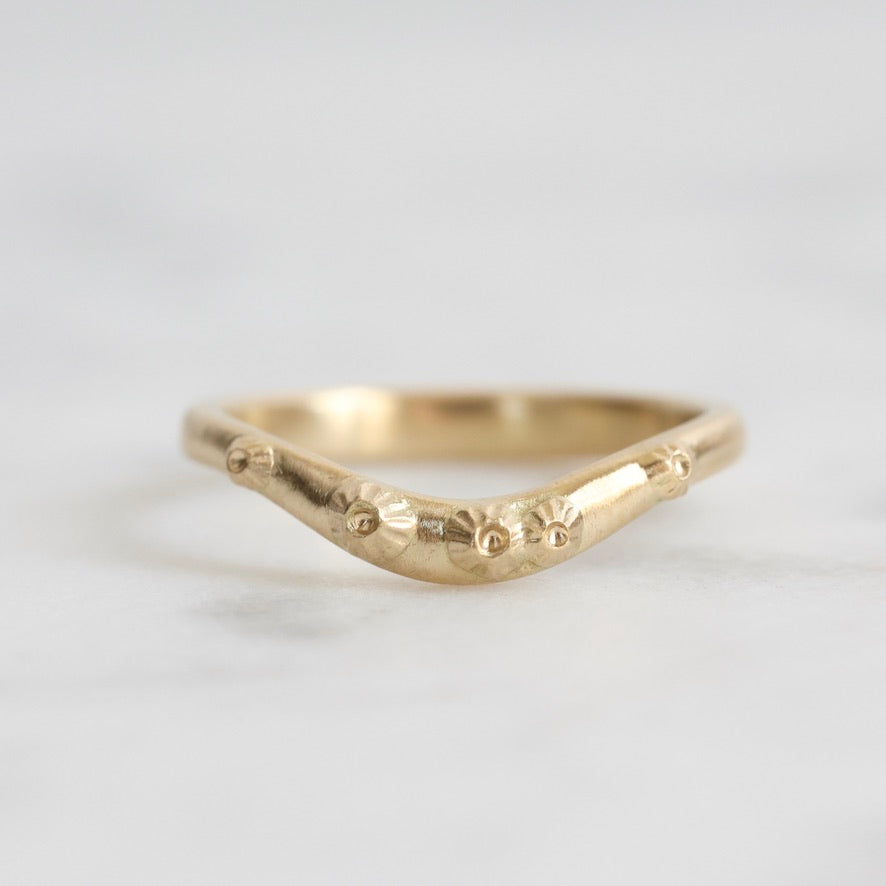 Gold ring with a unique design on a light gray background
