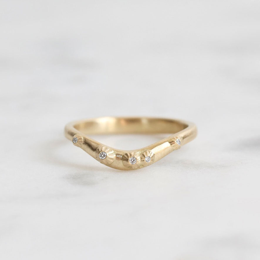 Gold ring with small diamonds on a light gray background