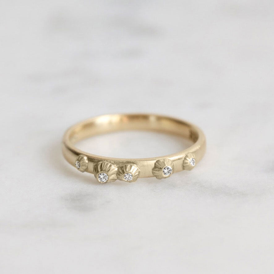 Gold ring with small diamonds on a light gray background