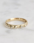 Gold ring with small diamonds on a light gray background