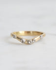 Gold ring with small diamonds on a light gray background
