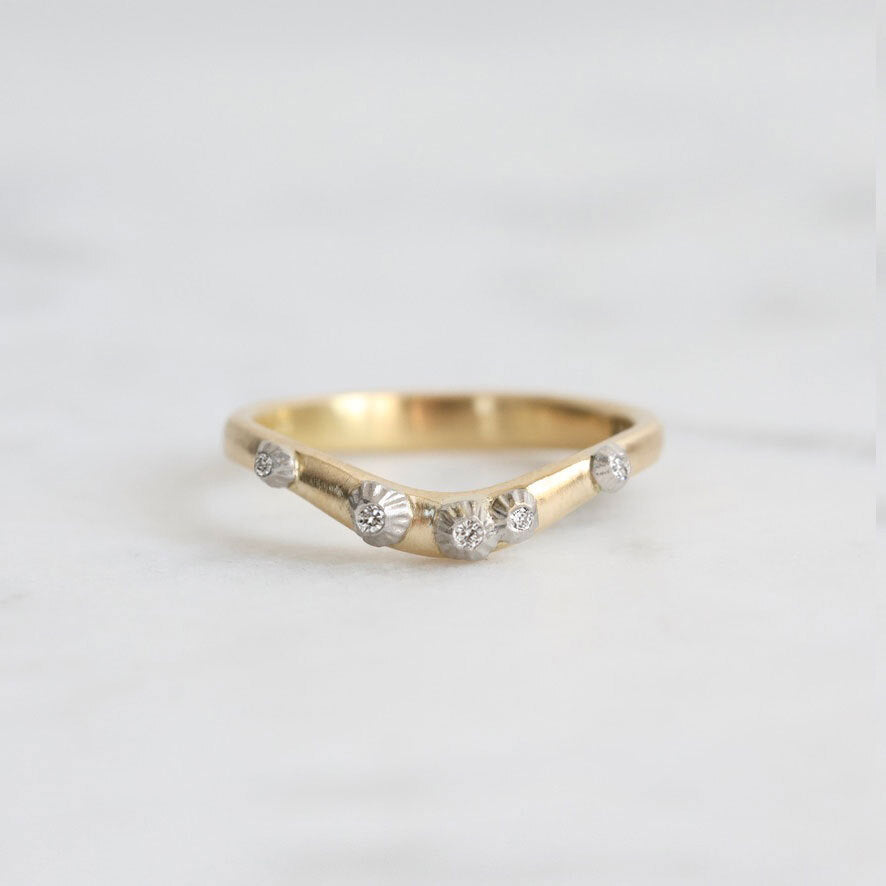 Gold ring with small diamonds on a light gray background