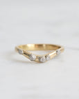 Gold ring with small diamonds on a light gray background