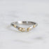 Platinum ring with gold accents and small diamonds on a light gray background