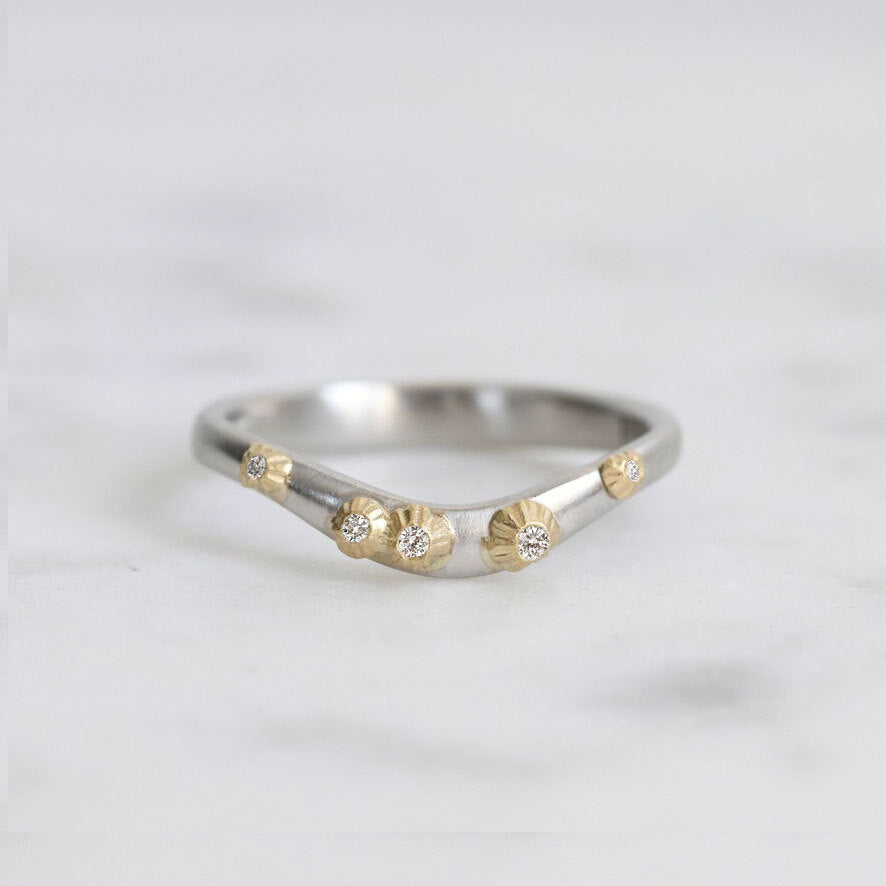 Silver ring with gold accents and small diamonds on a light gray background