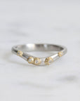 Silver ring with gold accents and small diamonds on a light gray background