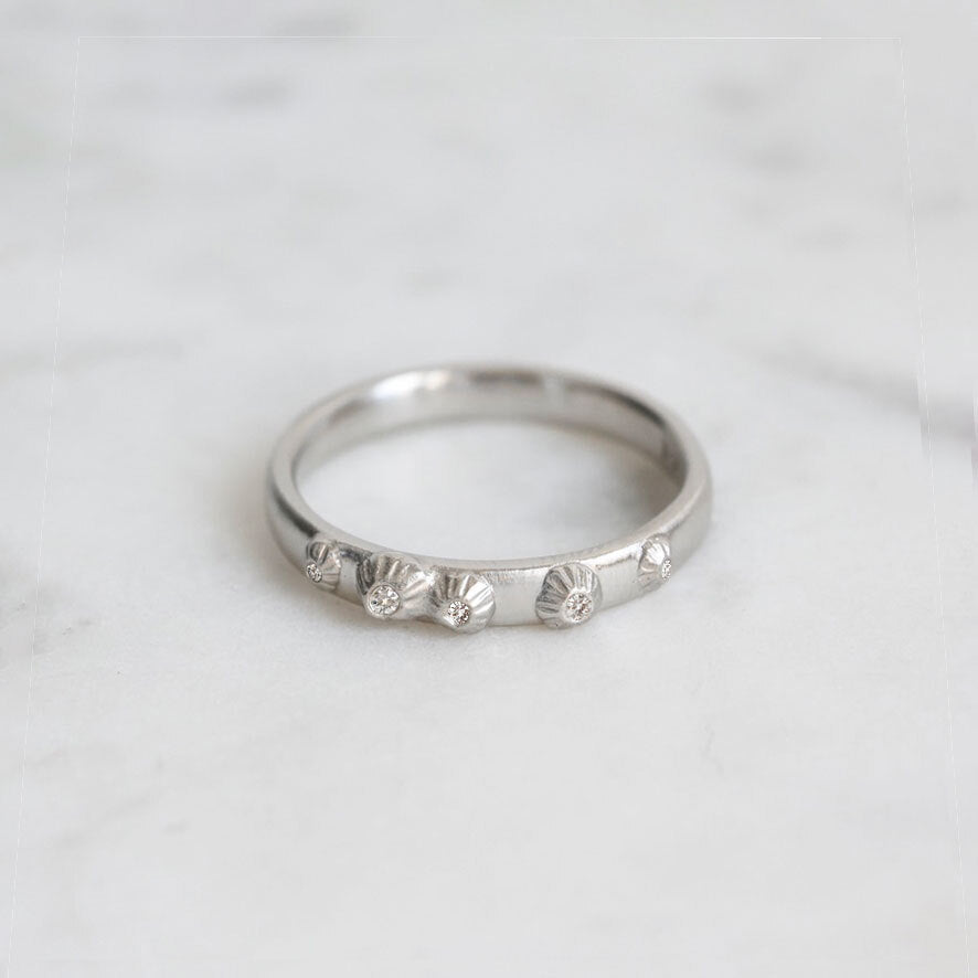 Silver ring with small diamonds on a light gray background